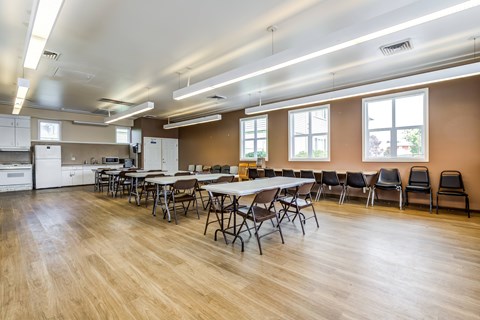 A large room with tables and chairs and a kitchen area.