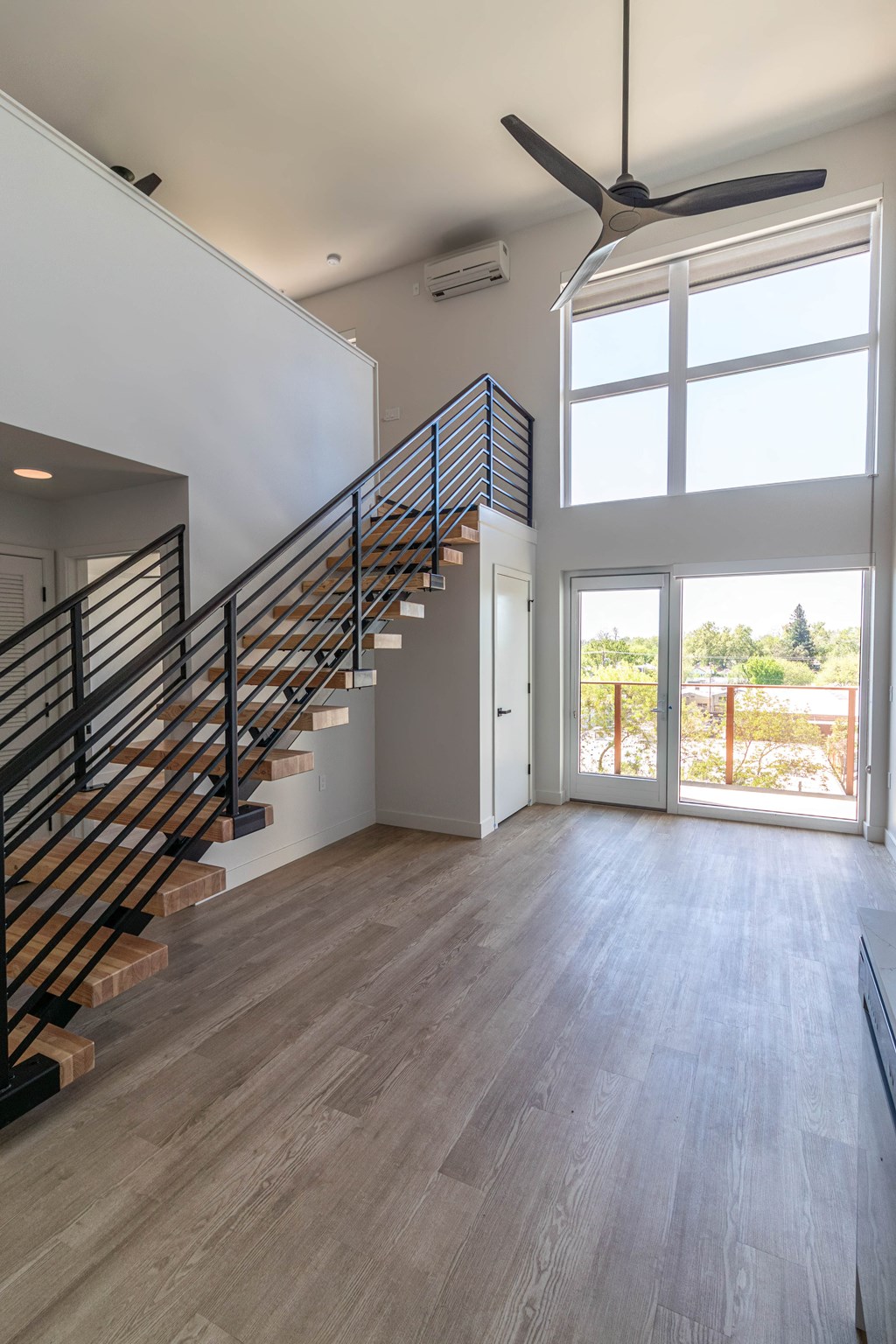 a living room with a staircase and a door to a balcony