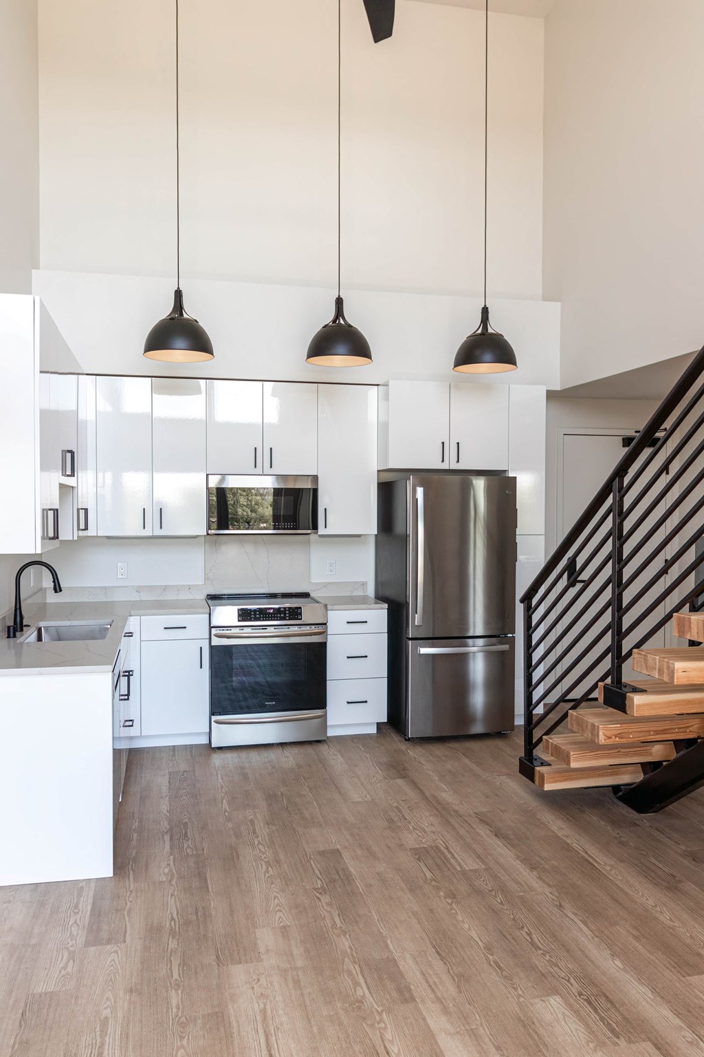 a modern kitchen with white cabinets and stainless steel appliances and stairs