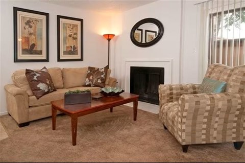 A living room with a couch, chair, and fireplace.