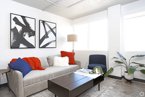A living room with a grey couch, a coffee table, and two abstract black and white paintings on the wall.
