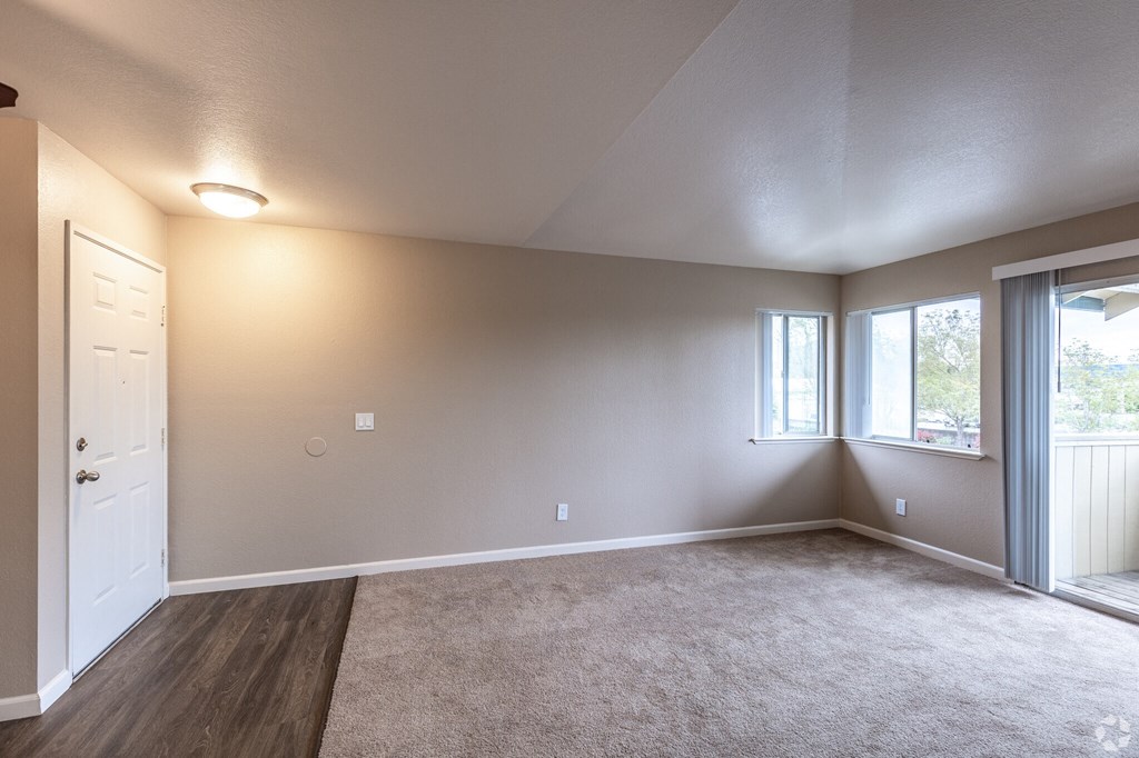 an empty living room with a door and window