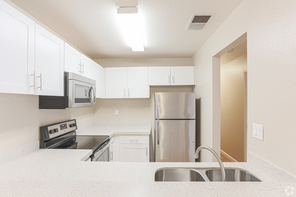 a white kitchen with stainless steel appliances and white cabinets