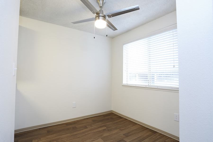 Des Moines, WA Apartments - Marina Club - Bedroom With Ceiling Fan, Wood Plank Flooring, And A Large Window