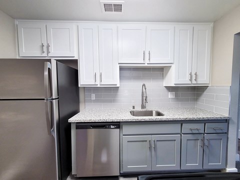 A kitchen with white cabinets and a stainless steel refrigerator.