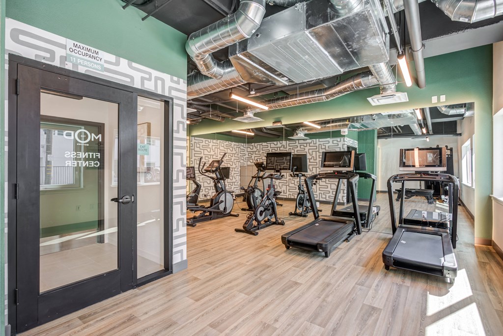 a gym with weights and cardio machines and a glass door