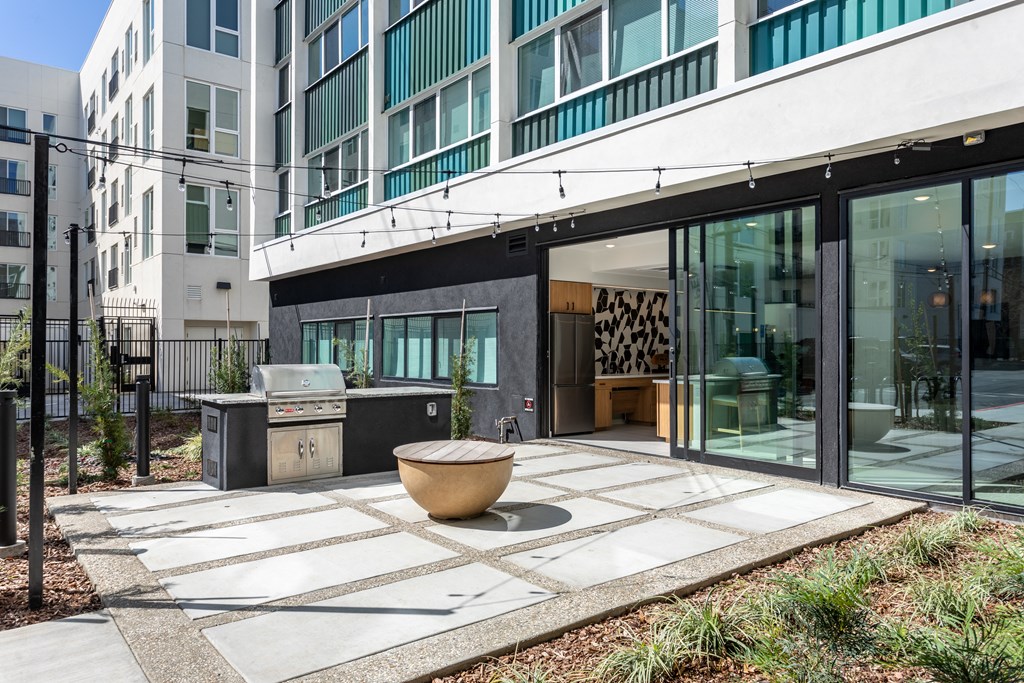 a patio with a grill and a table in front of a building