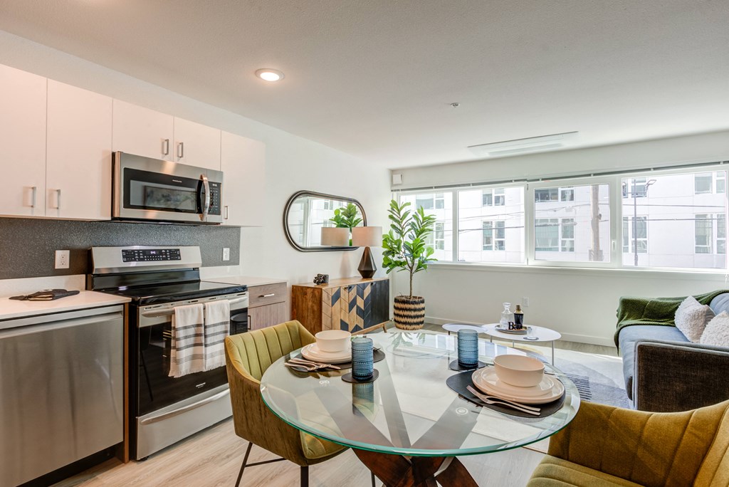 a kitchen and living room with a glass table and chairs