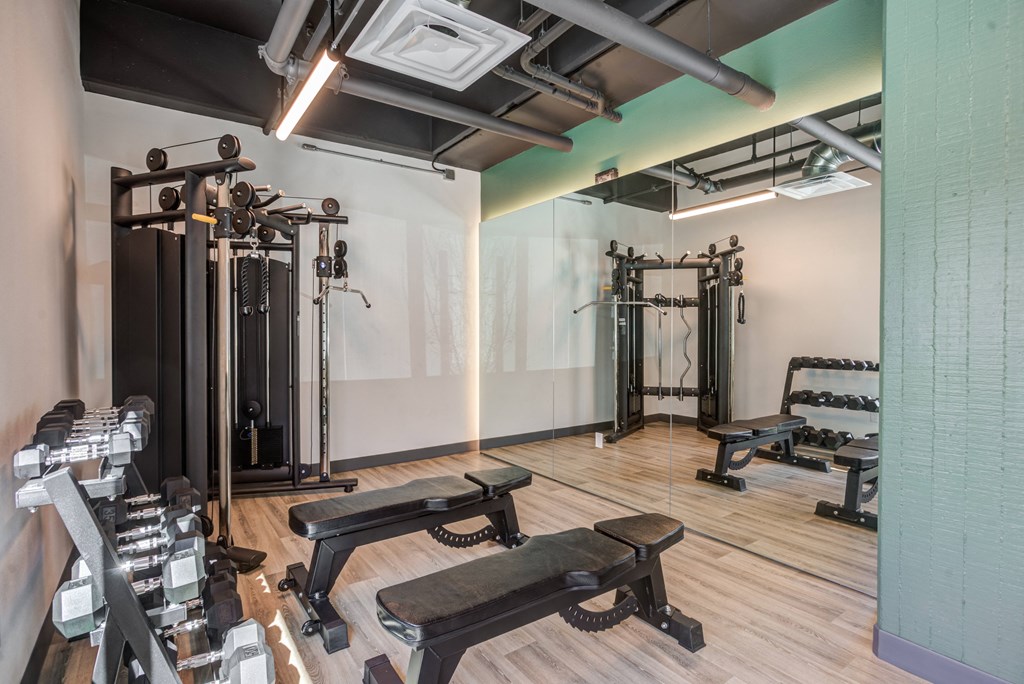 a fitness room with weights machines and a mirrored wall