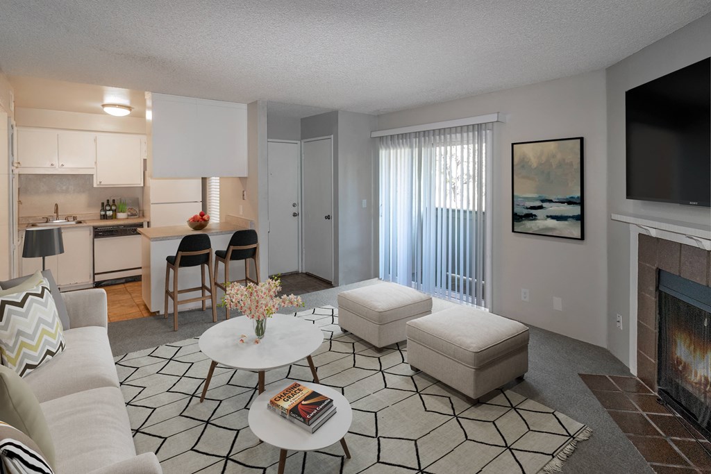 an open living room with a fireplace and a kitchen with a table and chairs