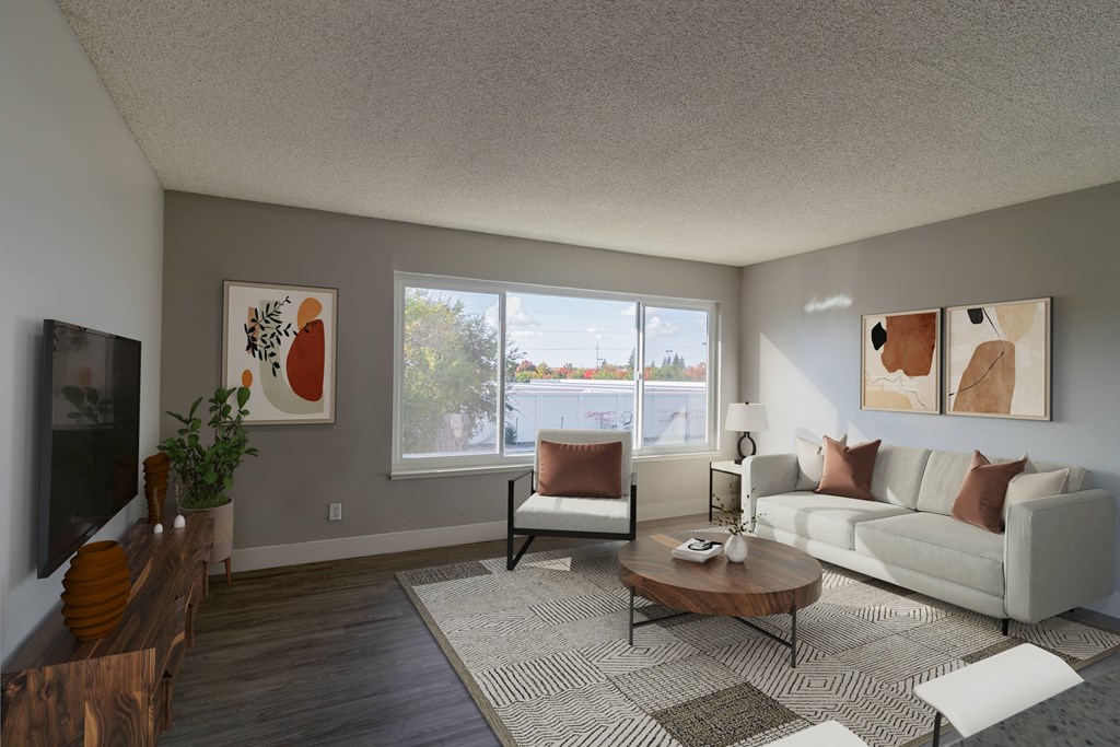 Arden Arcade CA Apartments - Mode - Spacious Living Room with A Couch, A Chair, A Large Area Rug, A Coffee Table, A TV Mounted On The Wall, And A Large Window To Let In Plenty Of Natural Light
