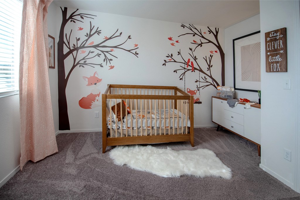 a nursery with a crib and a tree on the wall