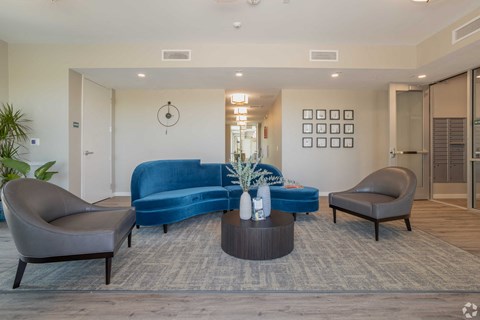A living room with a blue couch and two grey armchairs.