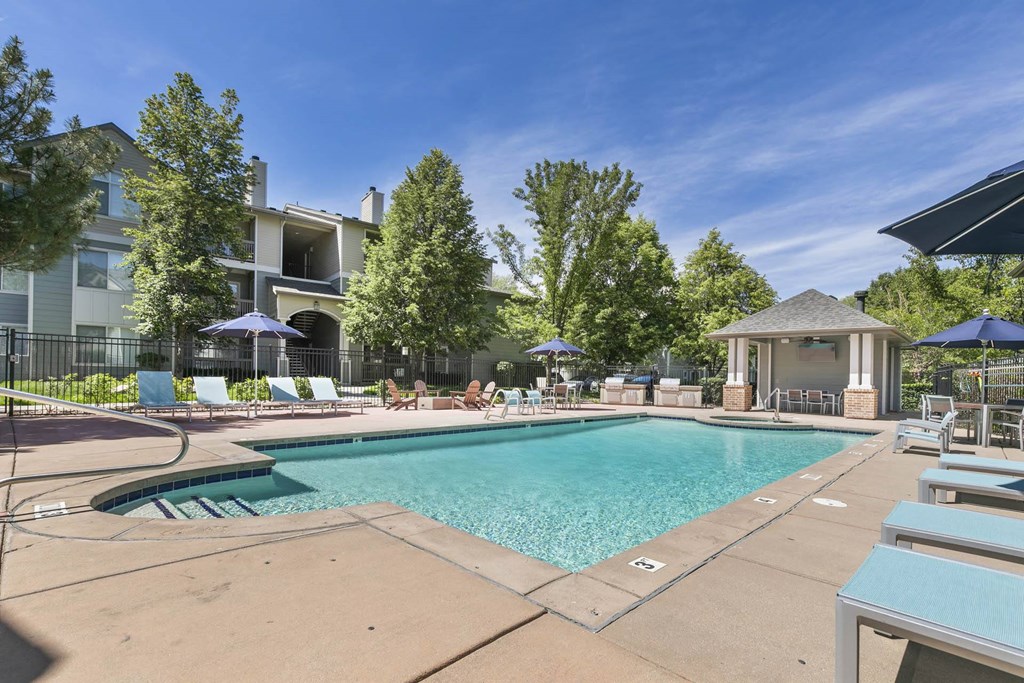 a swimming pool with chairs and umbrellas and a building in the background at Ascent Apartments, Cottonwood Heights, UT