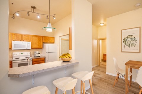 A kitchen with a counter and chairs.