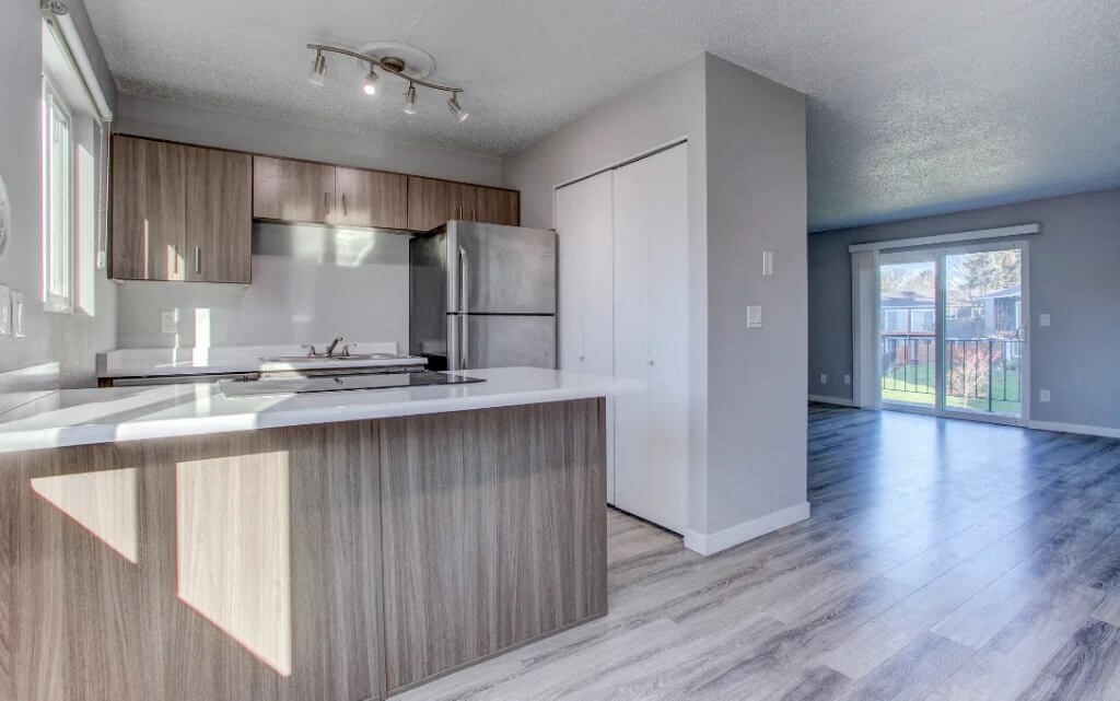 A modern kitchen with a white countertop and wooden cabinets.at Tigardville Apartments, Tigard Oregon