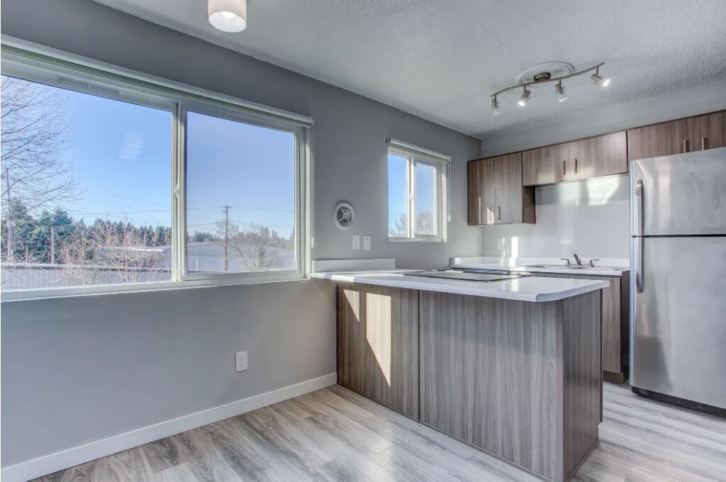 A kitchen with a large window and a refrigerator.at Tigardville Apartments, Oregon