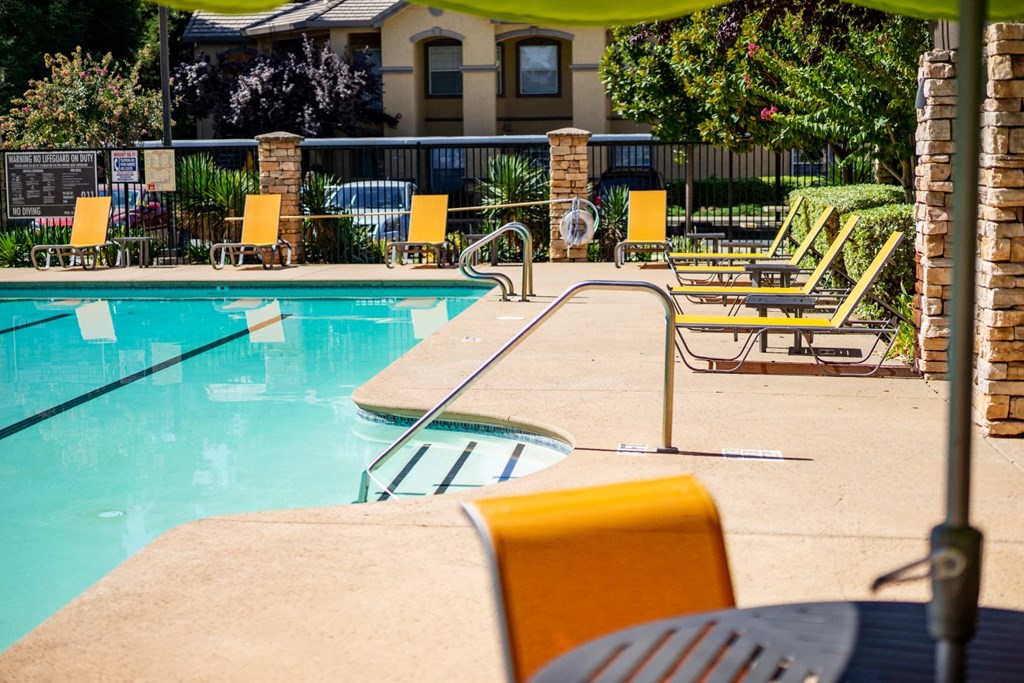 a swimming pool with lounge chairs and umbrellas