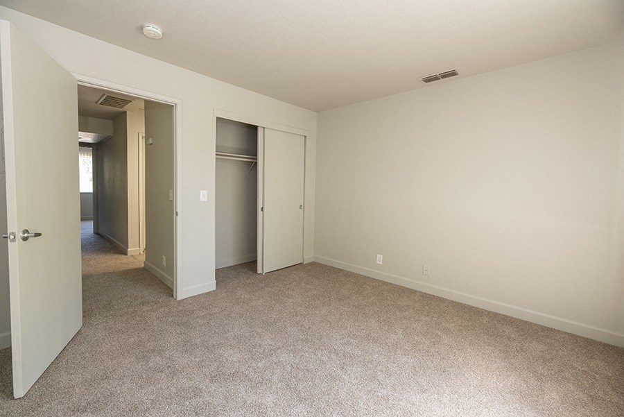 a bedroom with a carpeted floor and a door to a closet