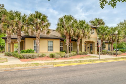 A building with a yellow facade is surrounded by palm trees.