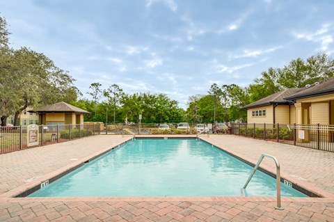 A large outdoor swimming pool surrounded by a brick border.
