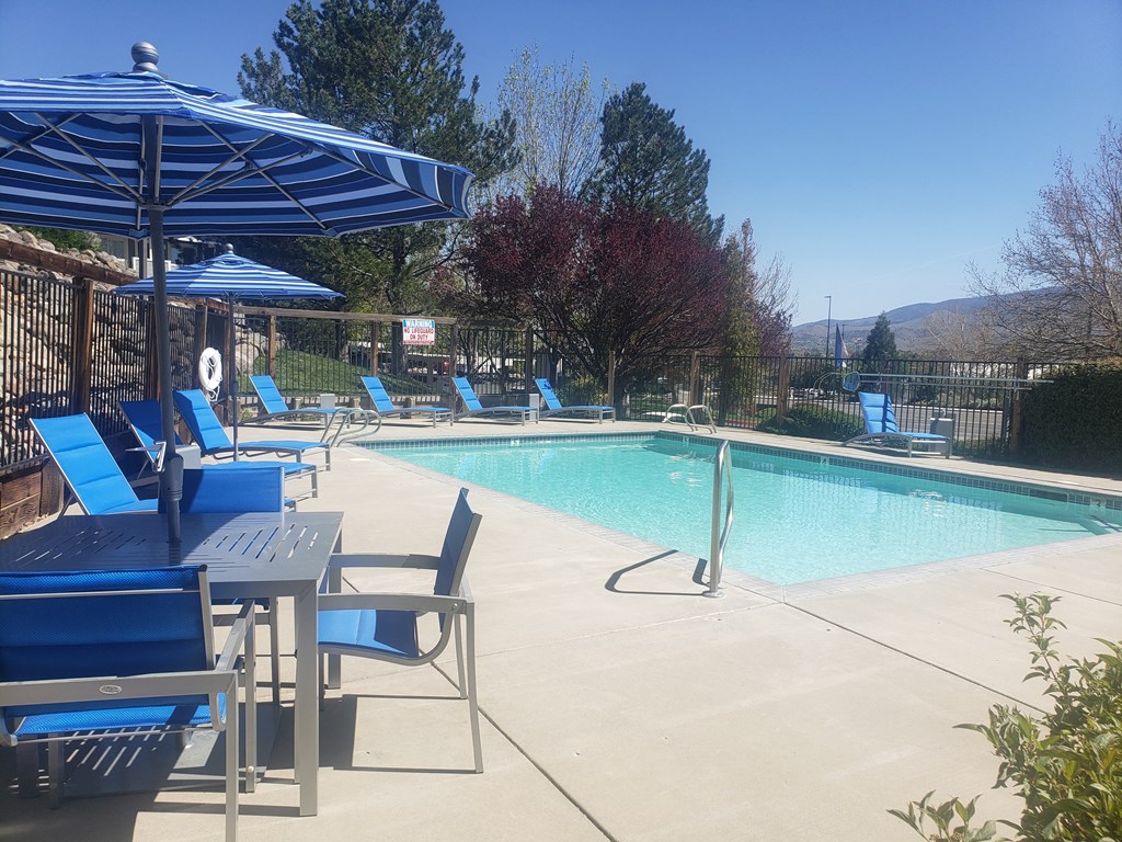 a swimming pool with blue chairs and umbrellas