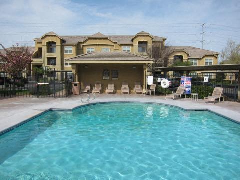 A swimming pool in front of a building with a fence around it.