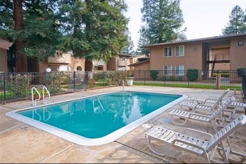 A swimming pool surrounded by a fence and chairs.