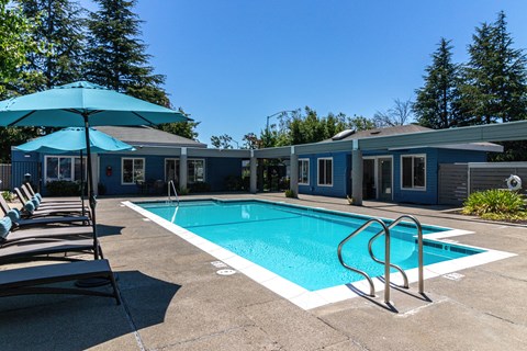 San Leandro, CA Apartments - Gateway Apartments - Pool with Blue Umbrellas, Lounge Chairs, and Lush Landscaping