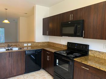 Preserve at Boynton Beach apartment home kitchen with blank appliances and dark wood cabinetry