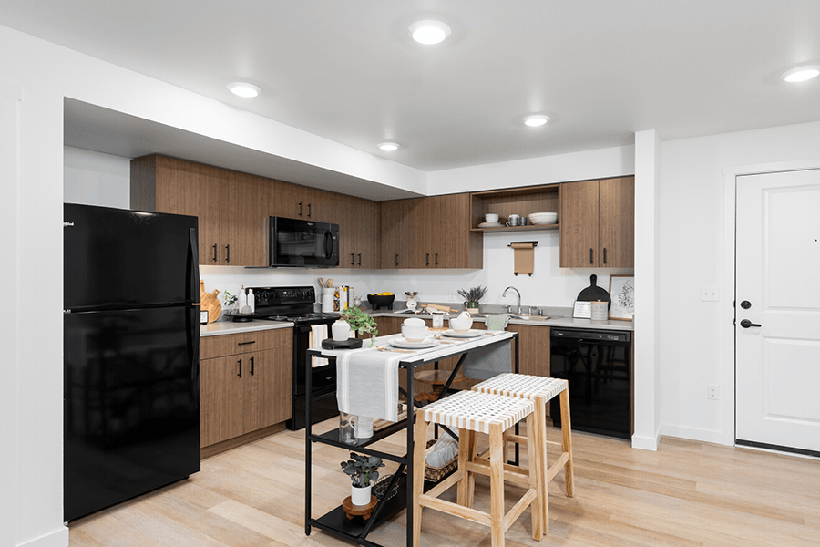 a kitchen with black appliances and a white table with two stools