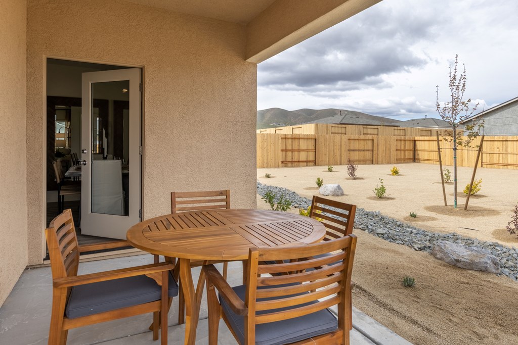 a patio with a wooden table and chairs and a wooden fence in the background