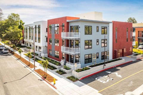 a rendering of a four story apartment building with red and gray exterior walls and balconies