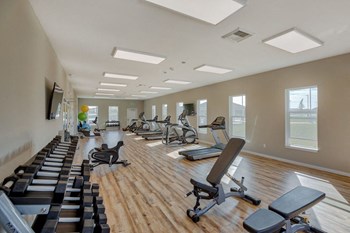 Apartments Near Sunset Park - Salish Flats - Resident Fitness Center With Dumbbells, Ellipticals, Treadmills, and Several Tall Windows - Photo Gallery 6