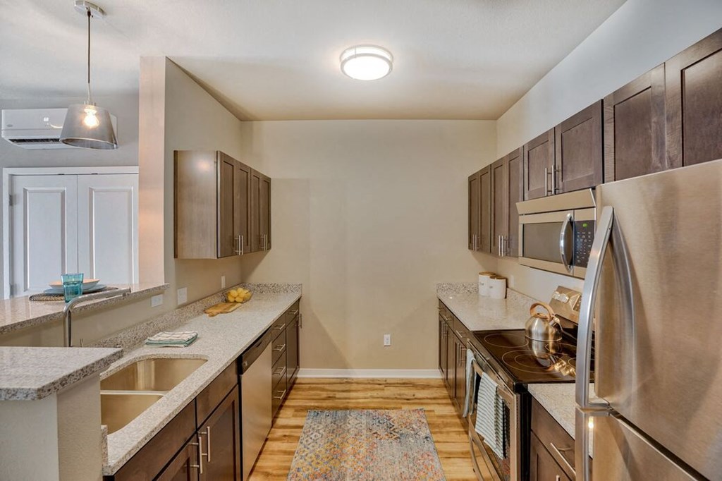 Airway Heights Apartments-Salish Flats-Kitchen with Stainless Steel Appliances, Hardwood Style Flooring, Wood Cabinets, and Overhead Lighting