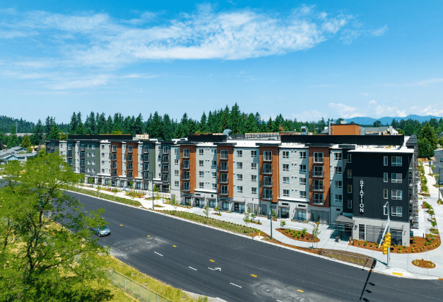 an aerial view of a row of apartment buildings with a road in the foreground at STATION BY VINTAGE, COVINGTON, WA
