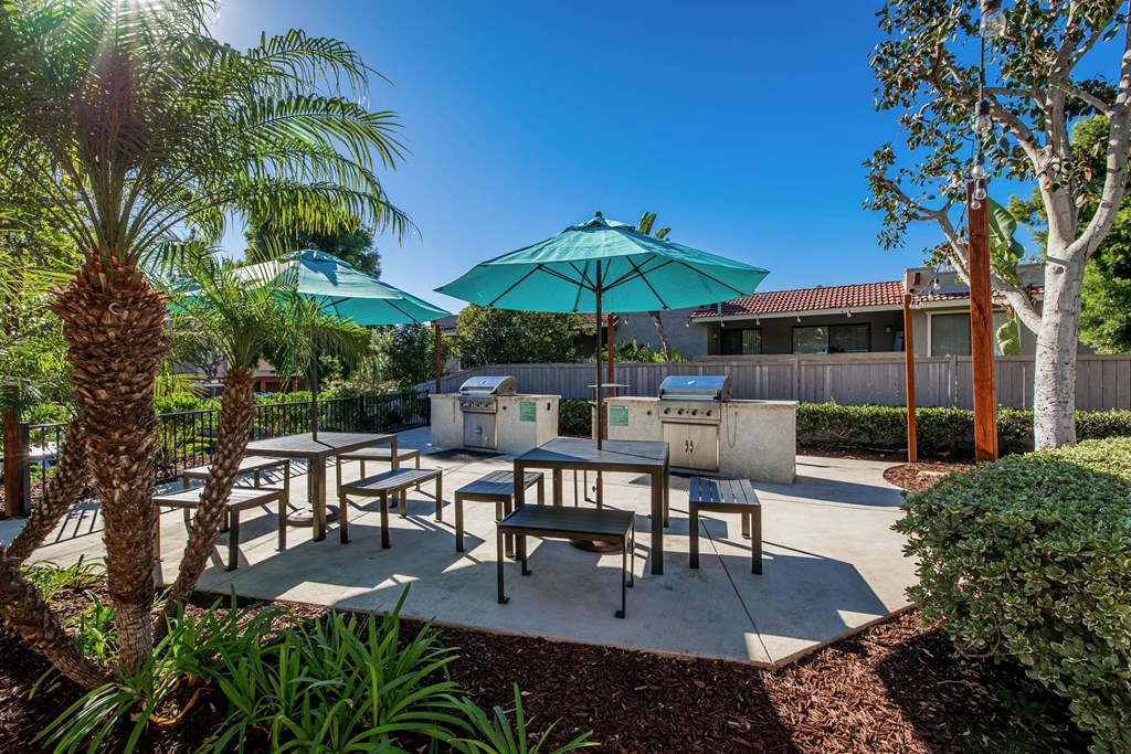 a patio with tables and umbrellas and a grill
