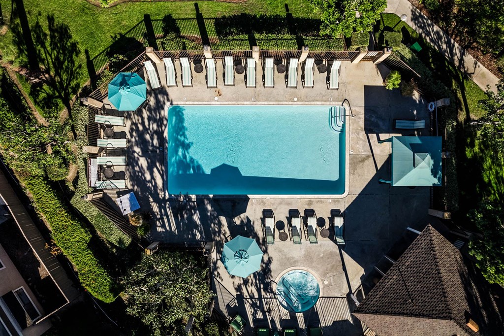 a birds eye view of a pool and patio with umbrellas and tables