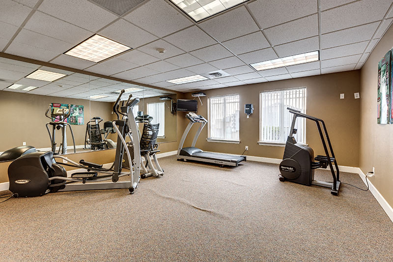 A spacious gym with a variety of equipment including treadmills, elliptical machines, and weights.