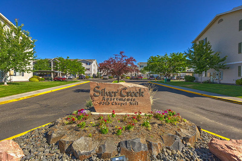 A sign for Silver Creek Apartment Homes stands in front of a road.