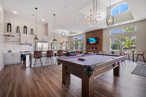 A pool table is in the middle of a room with a kitchen area.