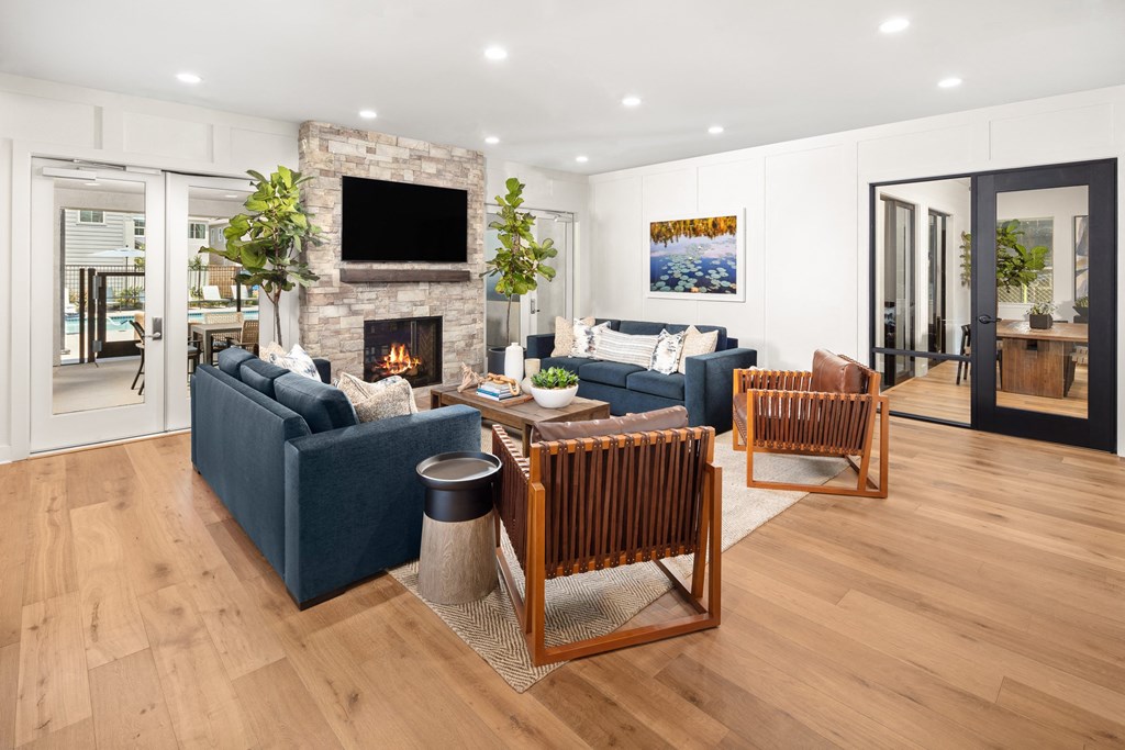 Brand New Apartments in Roseville, CA - Solstice at Fiddyment - Lounge Area with Blue Couches, Fireplace, and Wooden Chairs