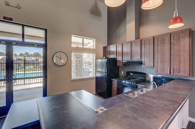 A kitchen with a black refrigerator and stove top oven.