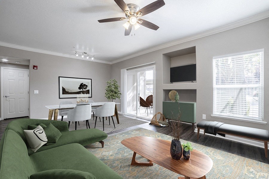 a living room with a green couch and a table and a ceiling fan