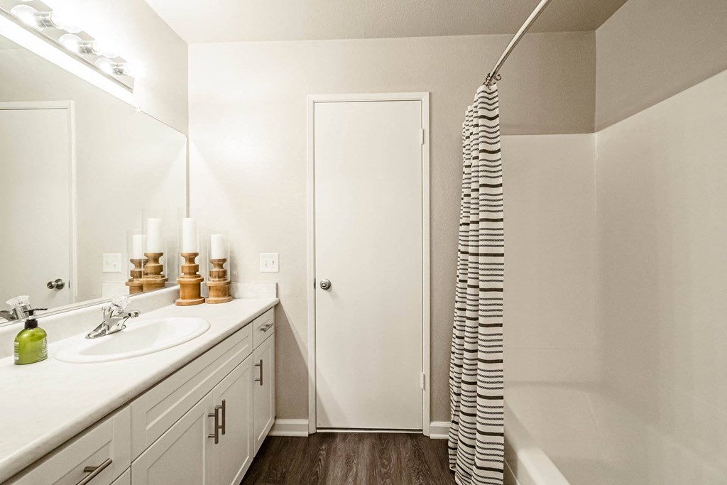a bathroom with a sink and a shower and a mirror at SYCAMORE GREENS APARTMENT HOMES, Vista