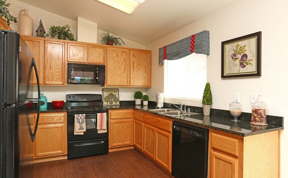 2 BR Apartments in Reno NV - Bungalows at Sky Vista - Kitchen with Brown Cabinets, Black Countertops, Black Appliances, and a Window.