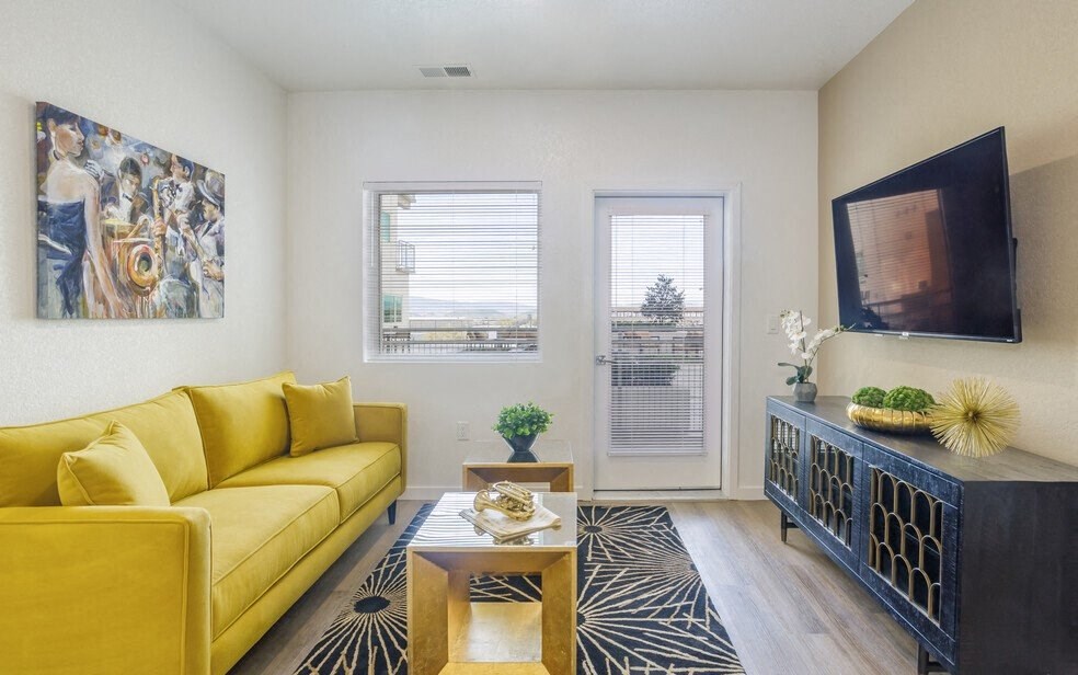 2-BR Apartments in Sparks, NV - The Deco - Furnished Living Room with Wood-Style Flooring, Glass Door to the Outside, Window, and Stylish Decor