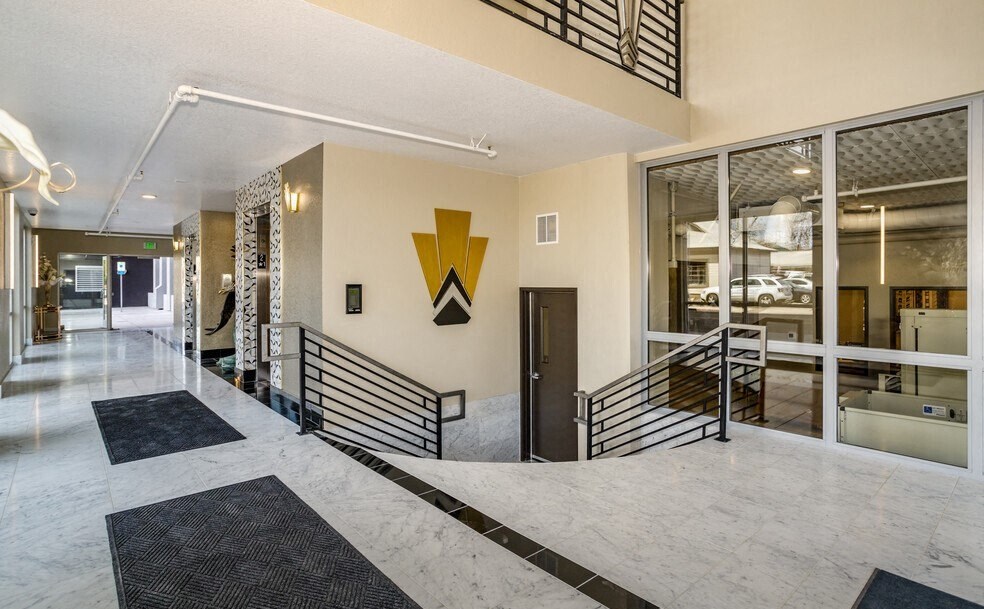 the lobby of a building with glass doors and a yellow logo on the wall