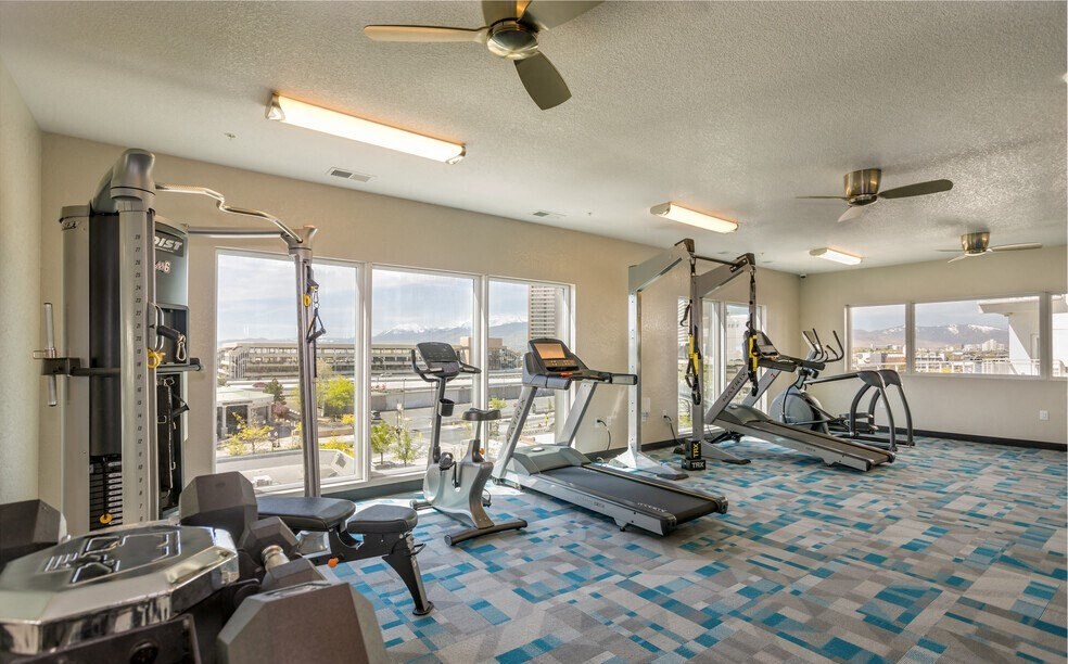 a gym with a view of the city and a ceiling fan
