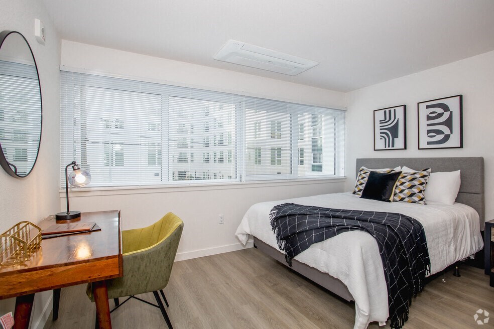1-Bedroom Apartments in Downtown Sacramento, CA - Mod at Midtown - Furnished Bedroom with Wood Plank Flooring, Wall to Wall Windows, White Walls, and Desk Area